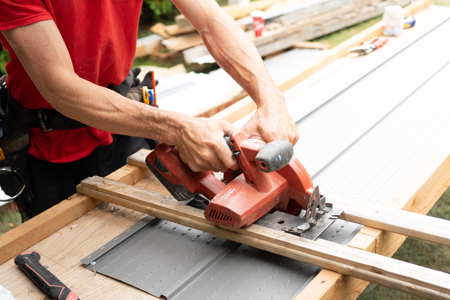 Carpenter cutting wood with a circular saw outdoors while repairing exterior trim ahead of hurricane season
